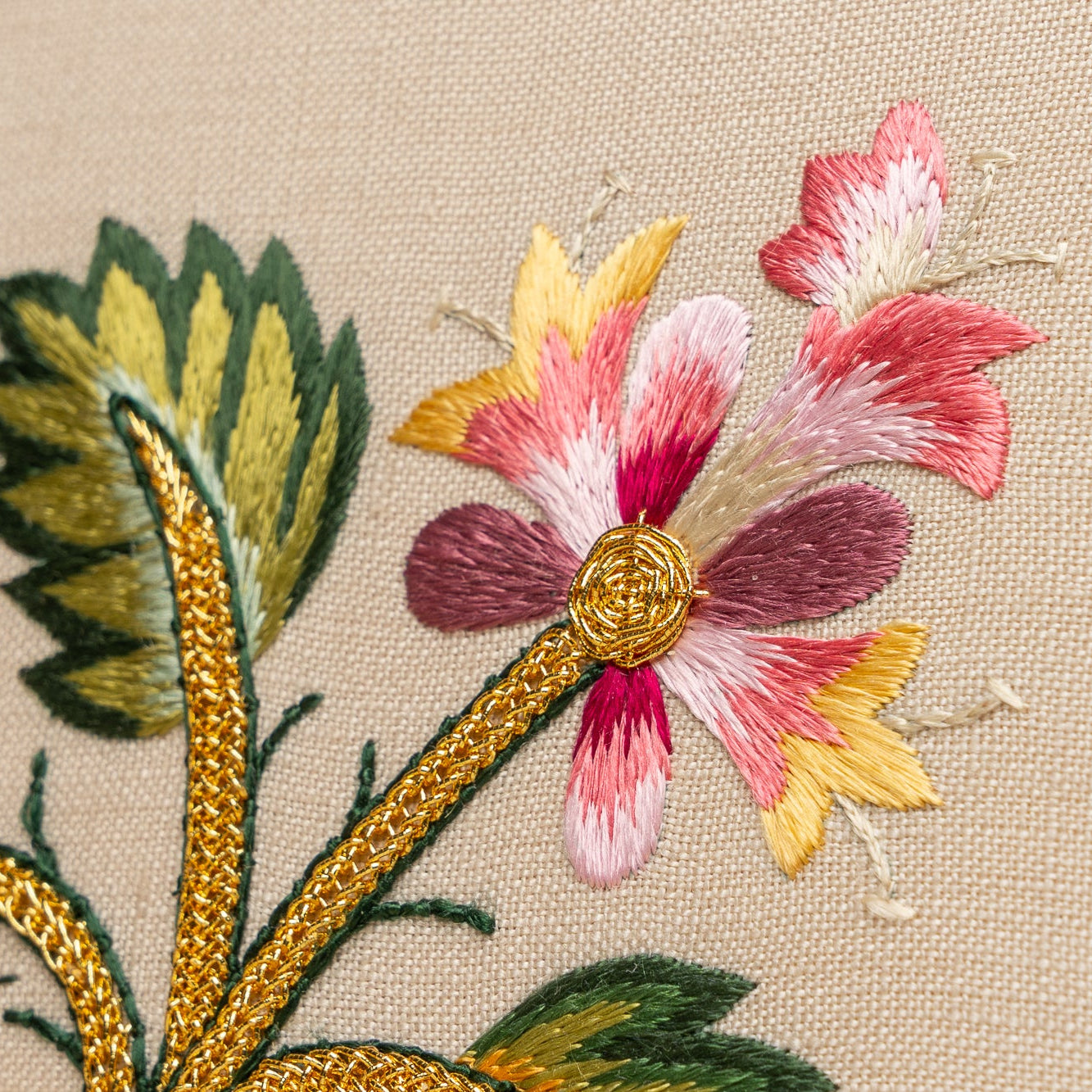 Close-up of embroidered flowers with gold accents on beige fabric