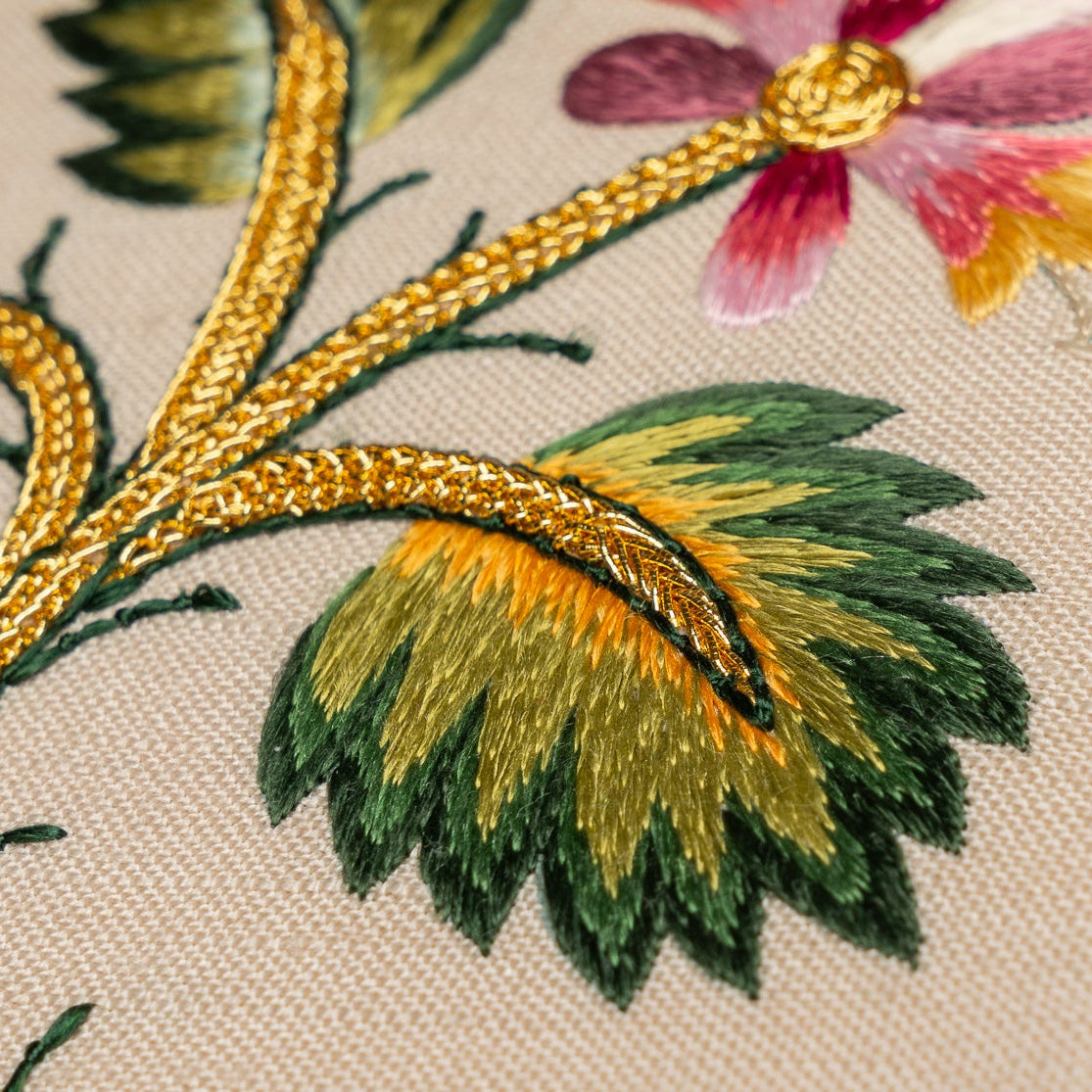 Close-up of embroidered floral design with gold thread on fabric
