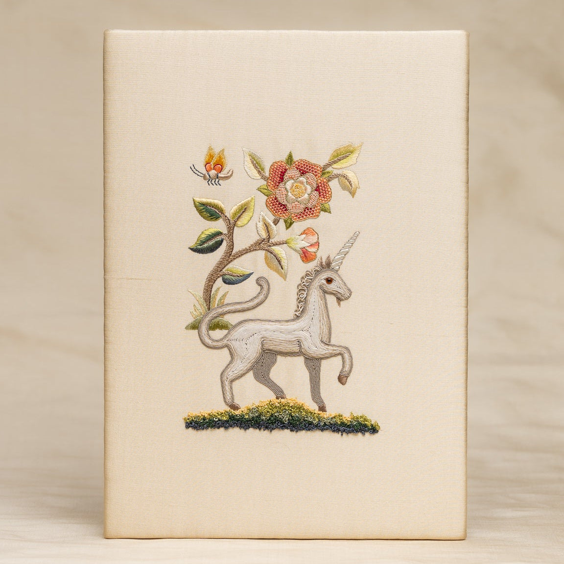 Decorative embroidery with a unicorn and floral design on a beige background
